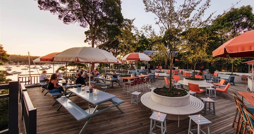 Photo of a Sydney cafe with empty tables and benches overlooking the water